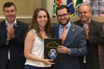 Matheus Erler entrega a moção de aplausos à técnica Helena Macchi