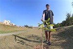 Gabriel mostra, orgulhoso, uma das mudas por ele plantada